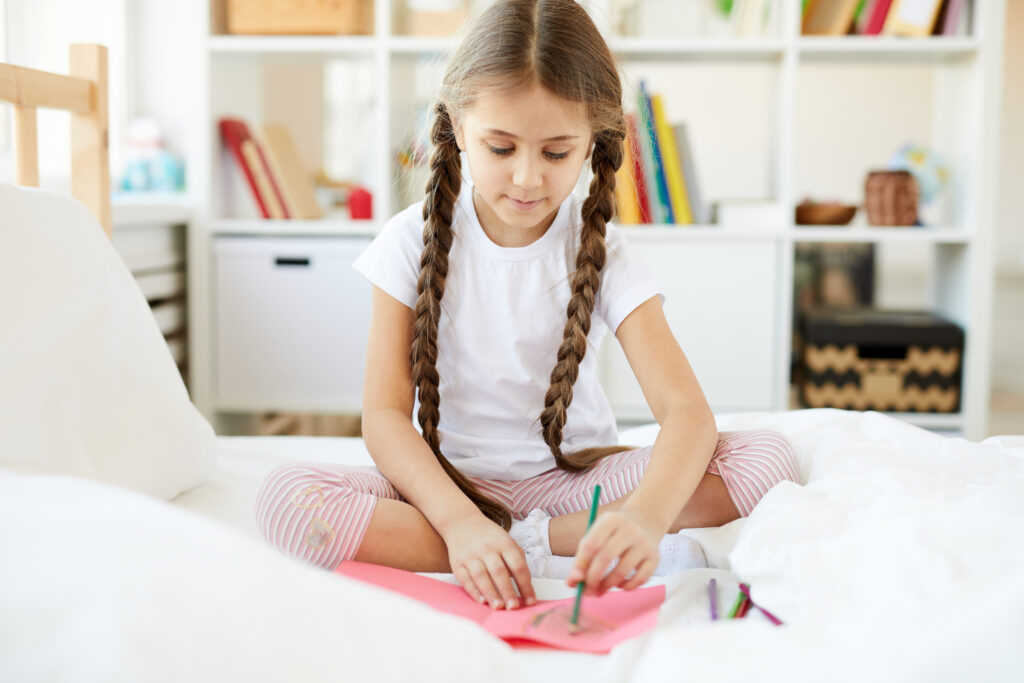 Dievčatko si kreslí v posteli. - envato.com