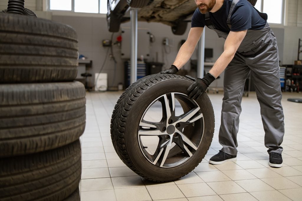 Mechanik v pneuservise odmontúva koleso z auta pri prezúvaní pneumatík.